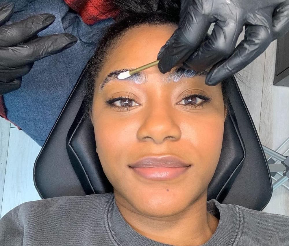 Client smiling during a brow tint application in the studio